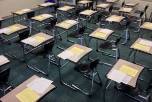 Image shows an exam hall with papers on the tables. 