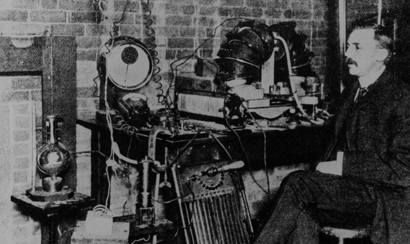 Image shows Rutherford sitting on a chair in a laboratory.