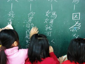 Image shows Chinese pupils writing on a blackboard.