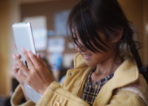 Image shows a girl using an iPad.