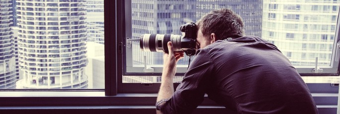 Image shows a man taking a photograph out of a window.