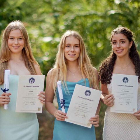 Students on an Oxford Summer School holding up their graduation certificates