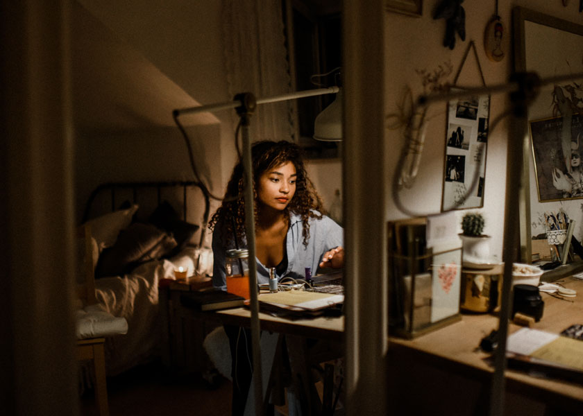 Una ragazza si siede a una scrivania nella sua stanza e pensa.